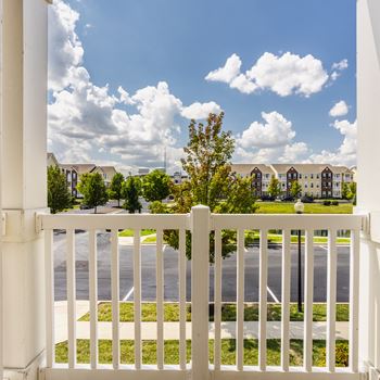 A white fence in front of a road with apartment buildings in the background